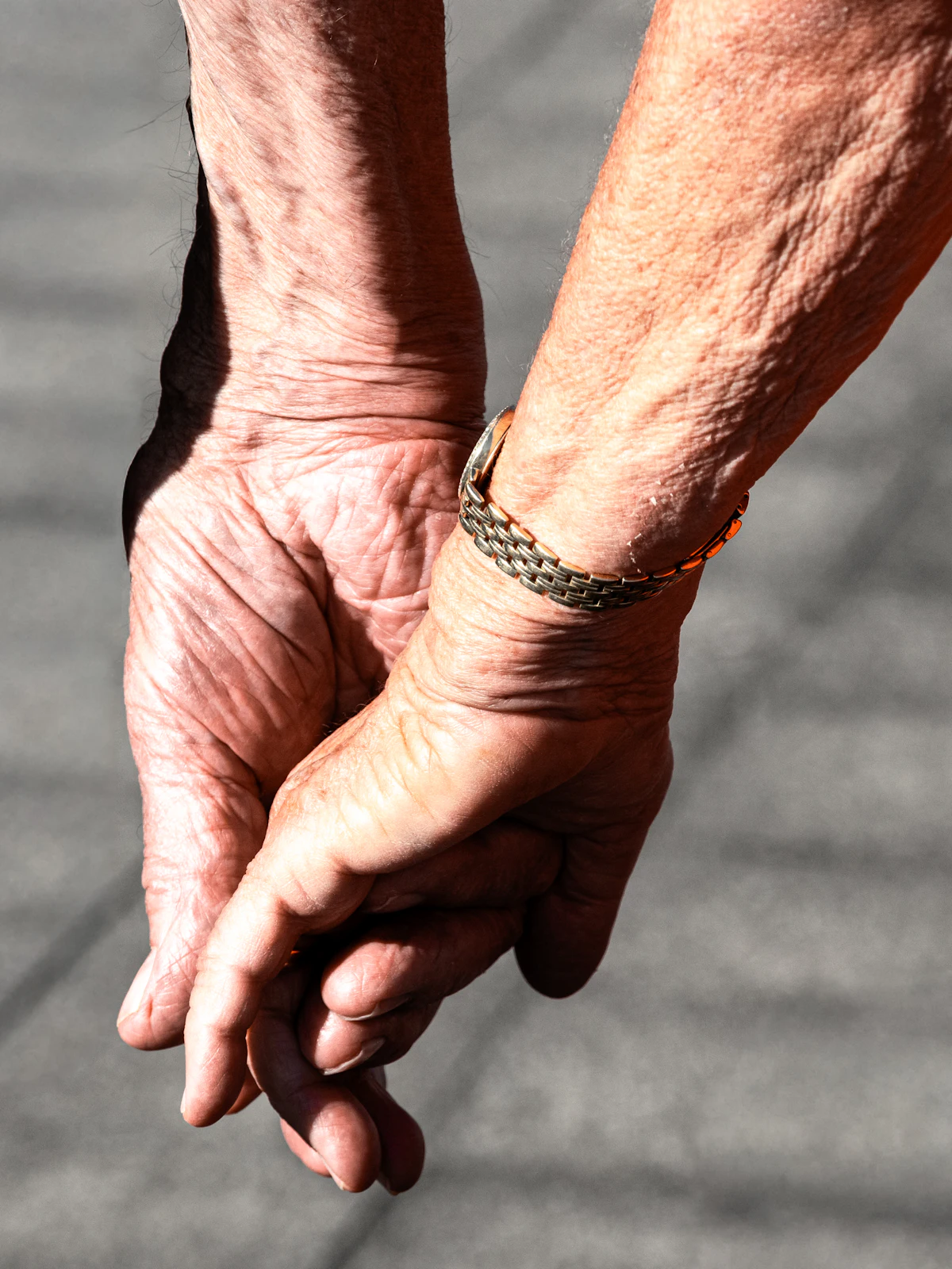 Two hands clasped together warmly in sunlight, a gesture of comfort and trust